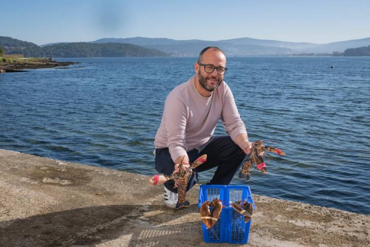 Fernando Ríos sujetando dos bogavantes al borde de la ría.