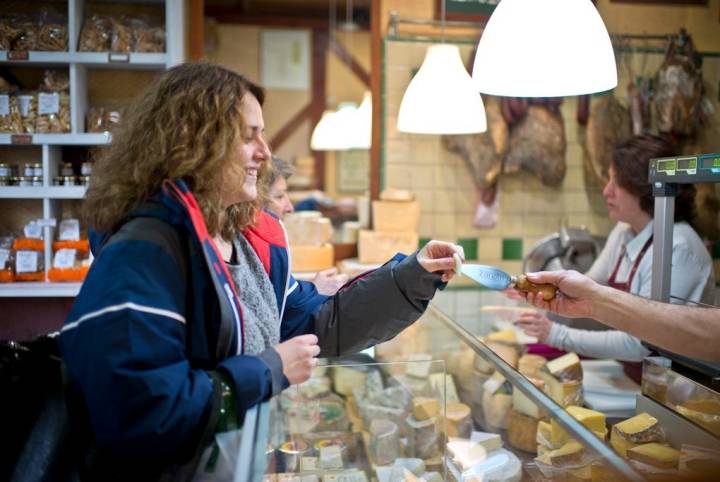 Raúl dando a probar a una clienta de León un queso de su tierra.