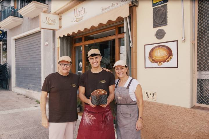 Carlos, Santi y Eva fuera de la tienda con un panettone.