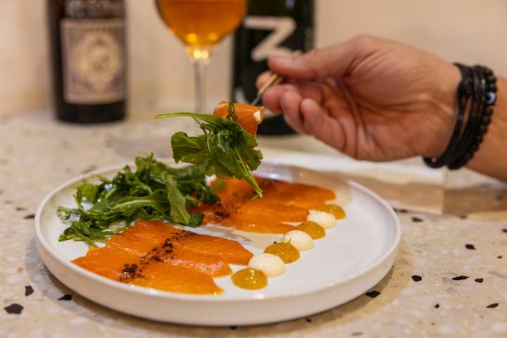 Un plato de salmón ahumado con salsas y lechuga.