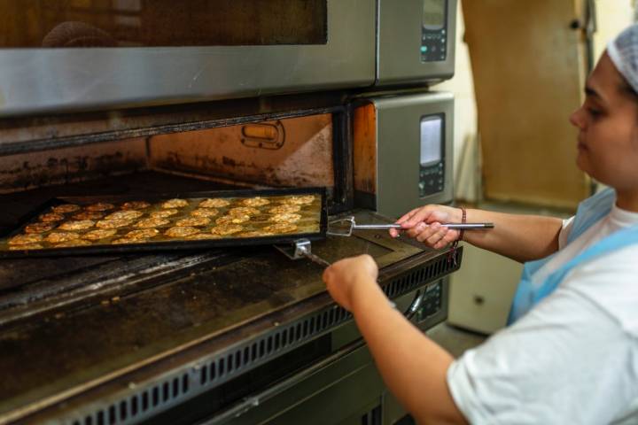 Una pastelera sacando del horno unos conraditos