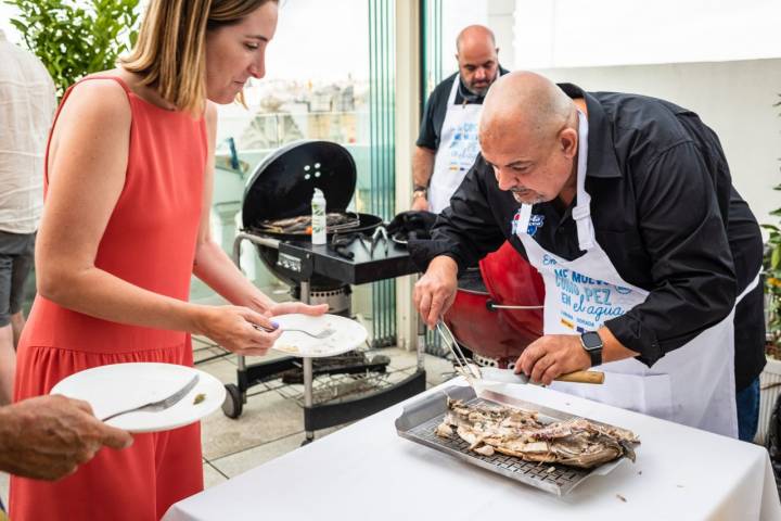 Sirviendo corvina a una mujer en una barbacoa de pescado