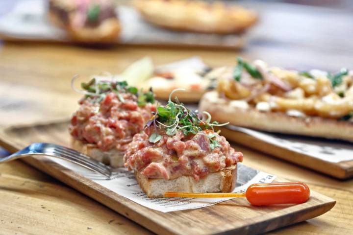 Una tosta de brioche con steak tartar, mayonesa picante y brotes verdes.