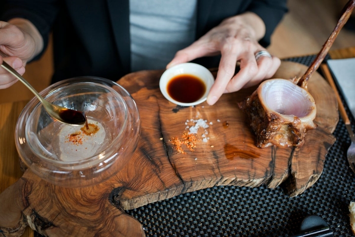 Un comensal mezcla en la mesa el tuétano con la salsa secreta de jengibre.