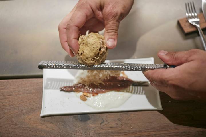 Anchoa del Cantábrico con base de 'stracciatella' y almendra garrapiñada con trufa rallada.