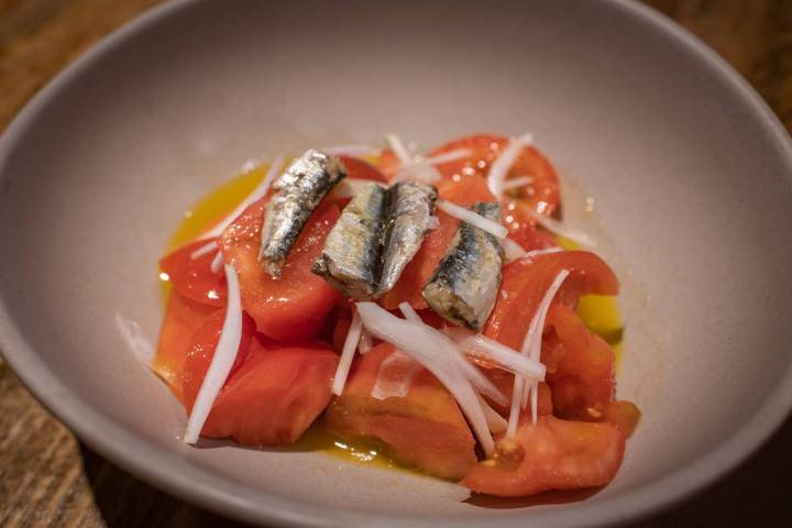 Ensalada de tomates, con sardinillas y cebolla.