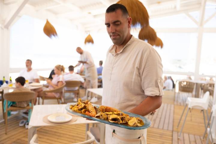 El camarero enseña un plato de frituras de mar