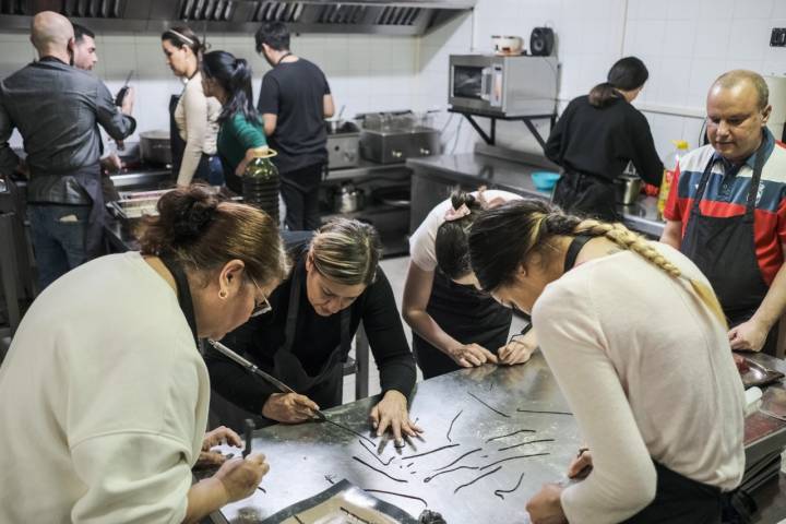 Varios alumnos concentrados mientras aprenden y trabajan en la cocina.