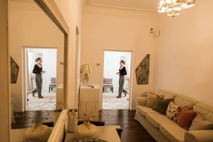 Pasillo del alojamiento con mujer al fondo reflejada, además, en un espejo.