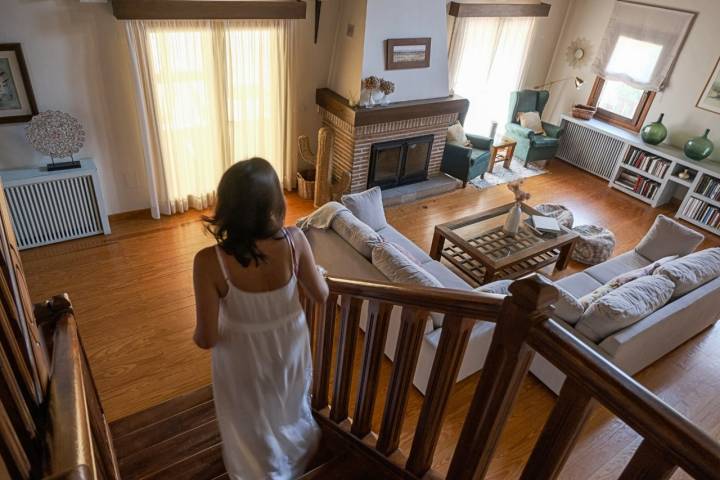 Una mujer baja por las escaleras de madera que dan al salón principal. 