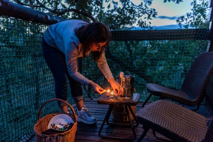 Una chica enciende unas velas en la terraza de la cabaña.