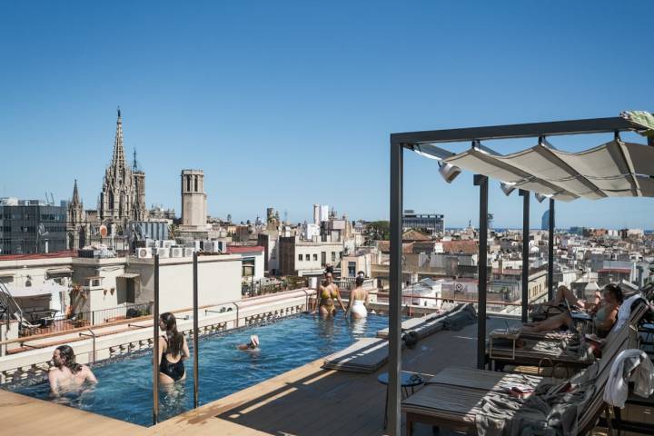 Varias personas se bañan en la piscina de la azotea con vistas 360º de la ciudad.