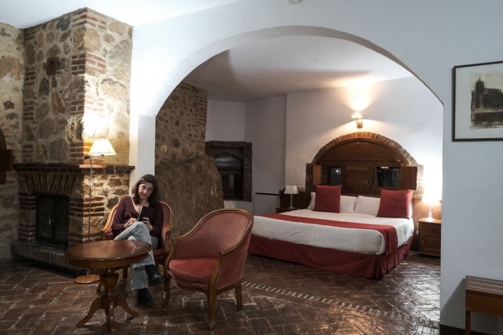 Una mujer está estada en uno de los sillones de una suite.