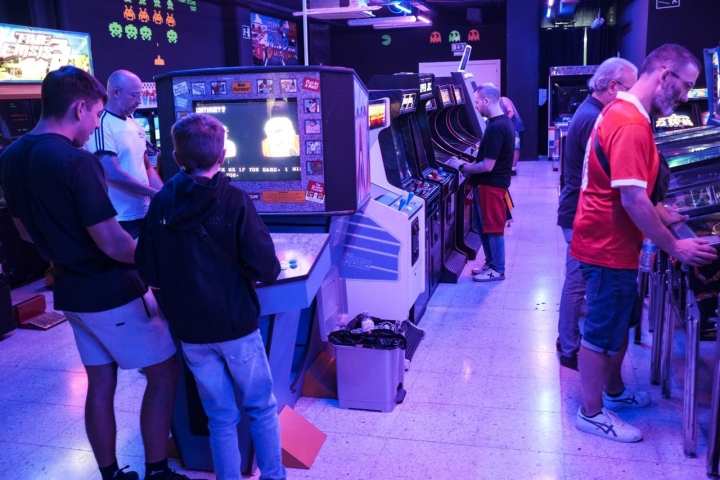 Varias personas de diferentes generaciones jugando en el salón más grande de los recreativos.