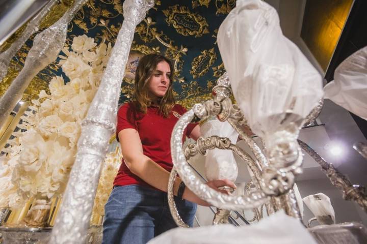 La joven auxiliar de priostía coloca los guardabrisas de los candelabros de cola del palio de la Virgen de Consolación.