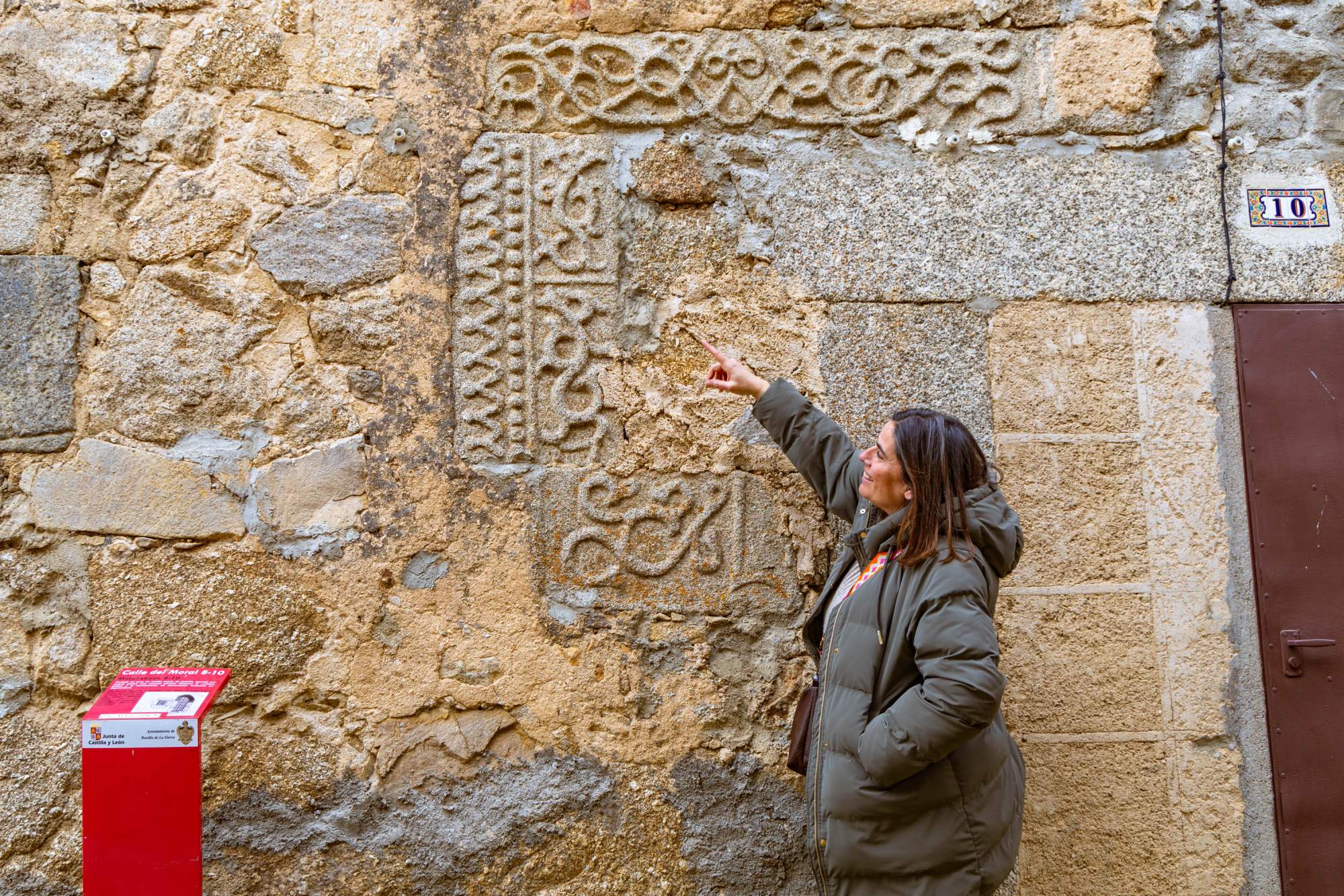 Julia Blázquez muestra unos bajorrelieves de estilo isabelino insertos en una de las fachadas de las casas de la calle Moral.
