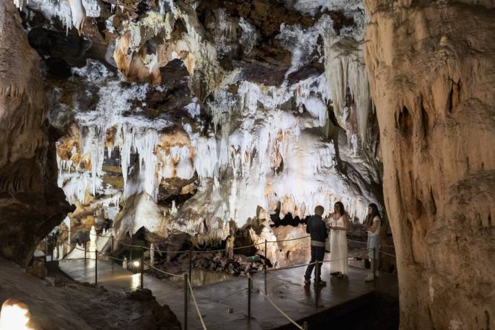 El guía con dos personas en una de las paradas del recorrido de la cueva.