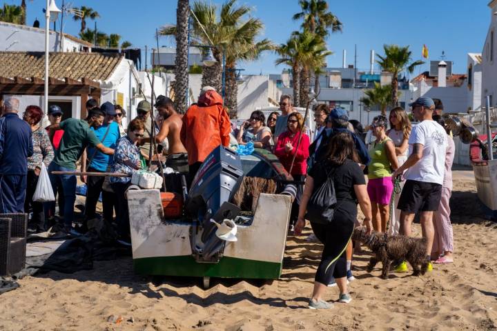 Barca de pescadores rodeada de curioso en una playa de Isla Cristina (Huelva)