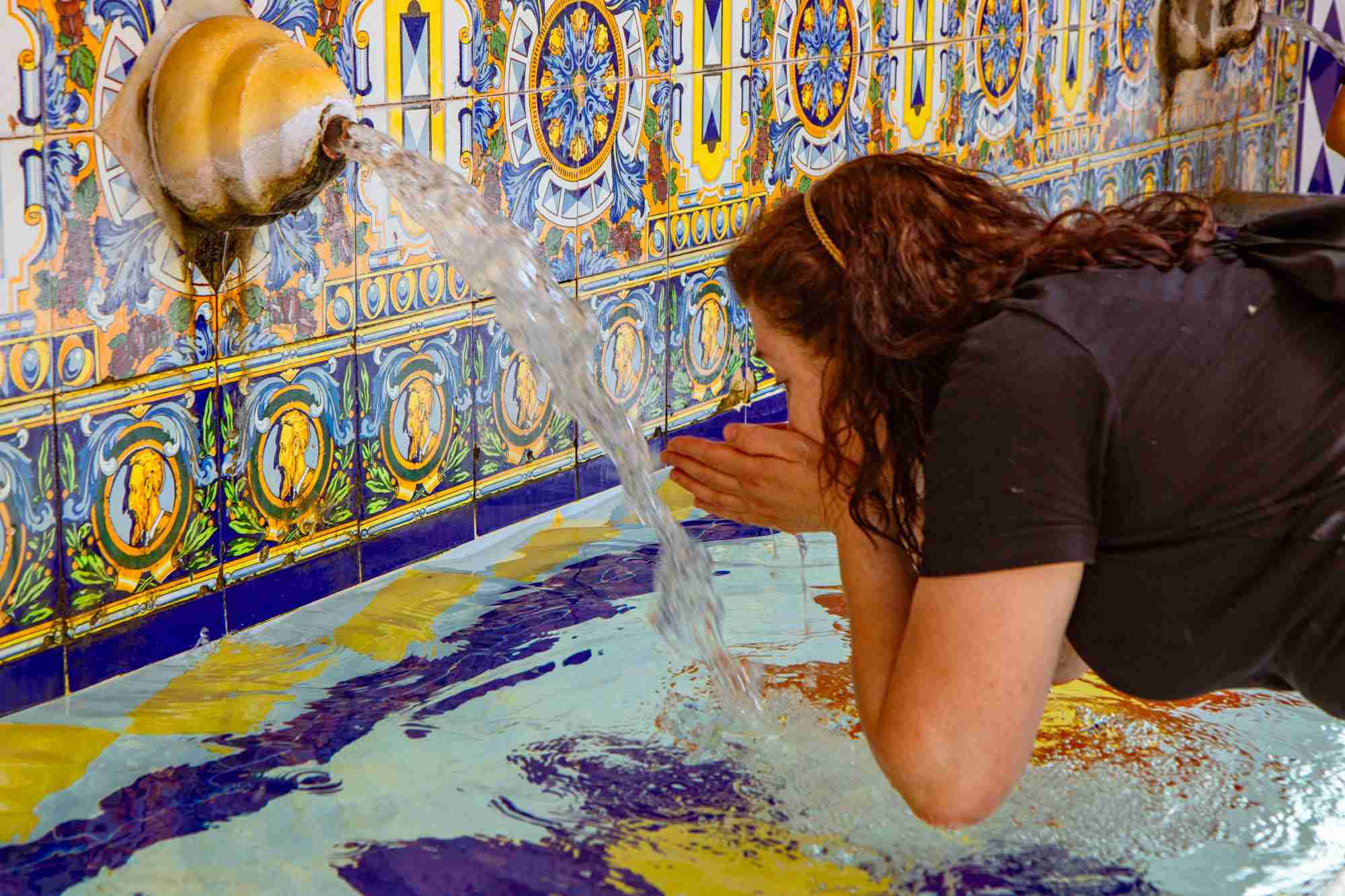 Mujer bebiendo agua de la fuente de El Pilar, en la plaza Mayor.
