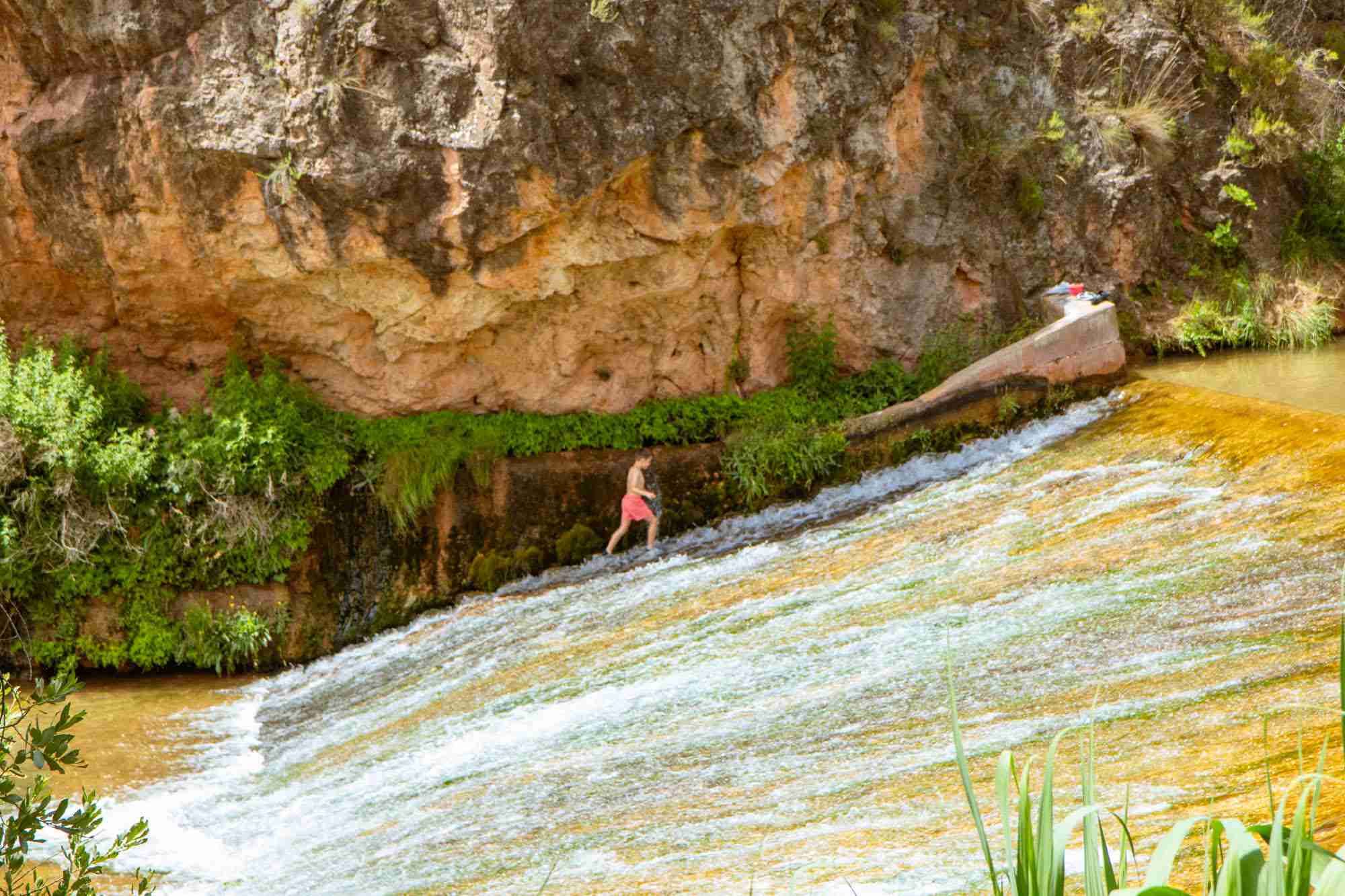 Niño subiendo por una pequeña cascada.