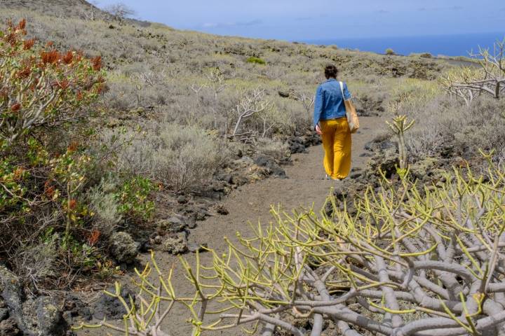 Una mujer camina por el sendero de tierra que lleve al Mirador de Lomo Negro II.