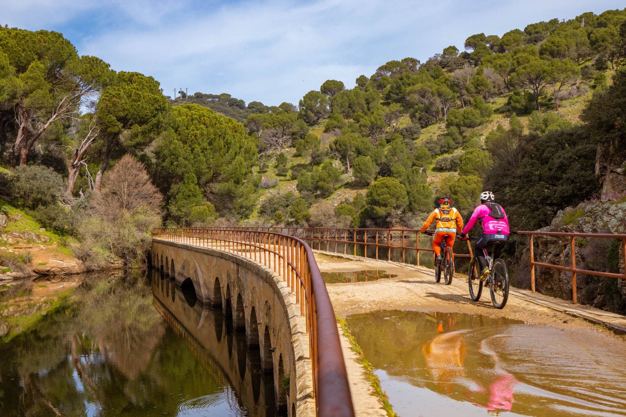 Dos ciclistas cruzan un puente por la ruta verde de Pelayos de la Presa (Madrid)