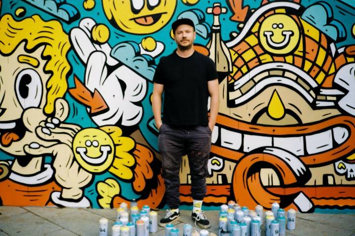 El artista DXTR frente a uno de sus muros en Barcelona