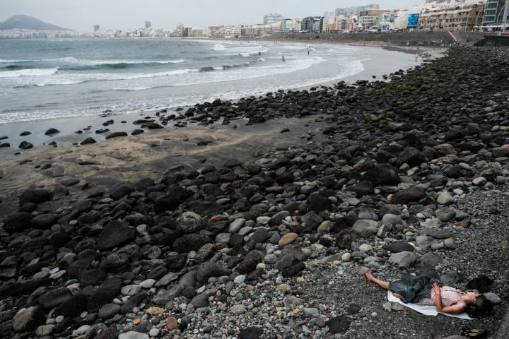 Una mujer descansa en una zona de la playa de Las Canteras.