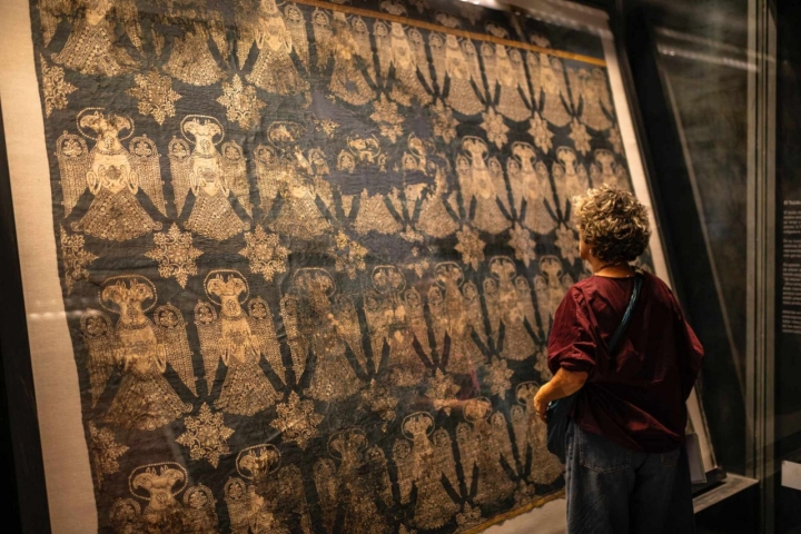 Una mujer mira las telas medievales de origen árabe del siglo X-XI. 