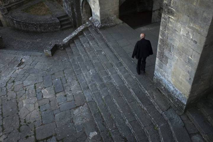 El párroco camina junto al pórtico de la Iglesia de San Esteban.